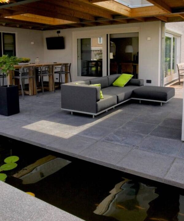 Little Island surrounded by a pond with a fireplace and a sofa in the middle on dark grey slabs