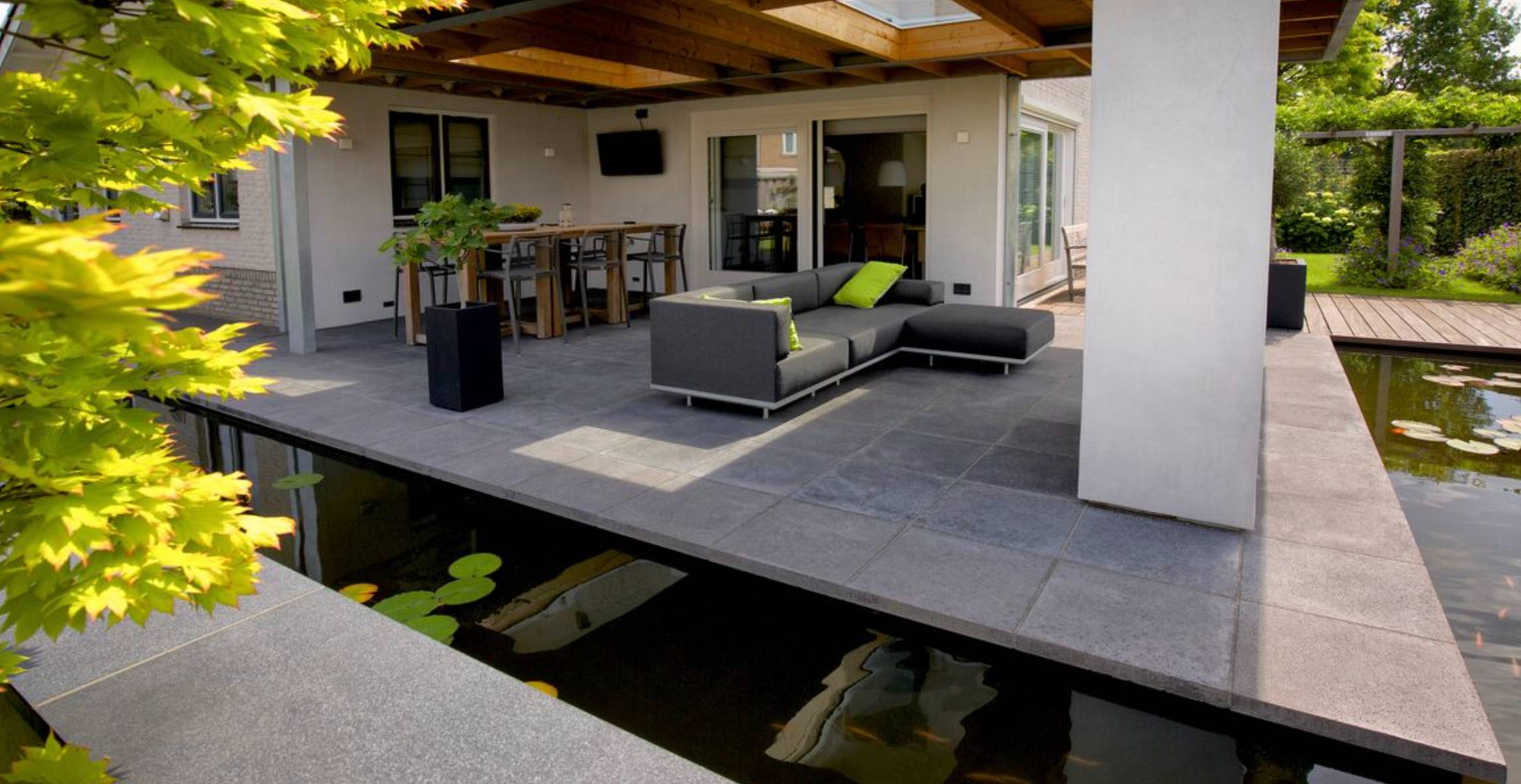 Little Island surrounded by a pond with a fireplace and a sofa in the middle on dark grey slabs